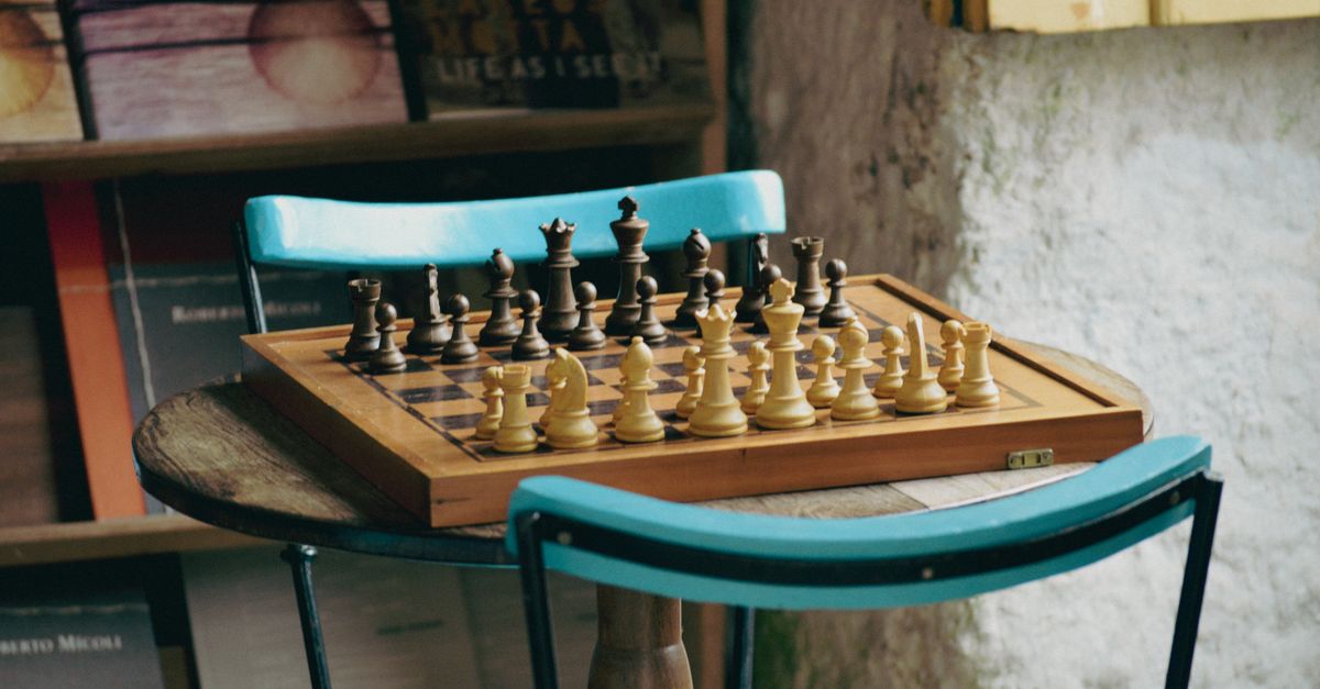 Chessboard with pieces set for play on a wooden table in a cozy rustic indoor setting.